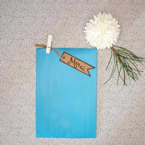 Sachet turquoise avec étiquette kraft de remerciements et petite pince en bois blanc