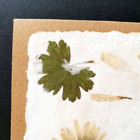 Détail de la carte artisanale avec fleurs séchées.