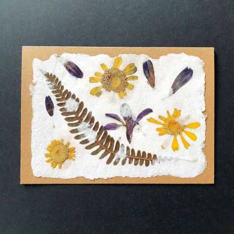 Carte double en papier artisanal avec inclusions florales.