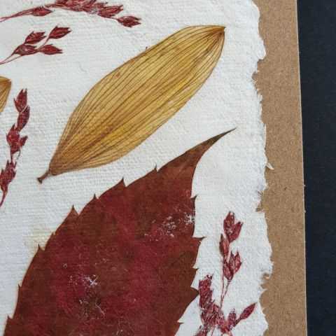 Détail de la feuille rouge en inclusion dans le papier artisanal qui compose la carte.