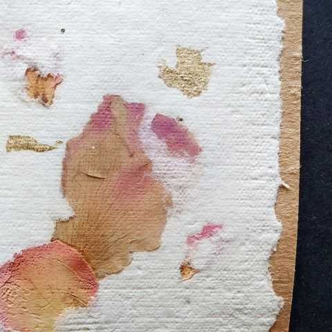 Détail de pétales de rose et éclats dorés sur papier artisanal pour étiquette.