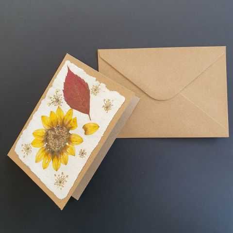 Présentation d'une carte artisanale sur kraft avec fleurs séchées.